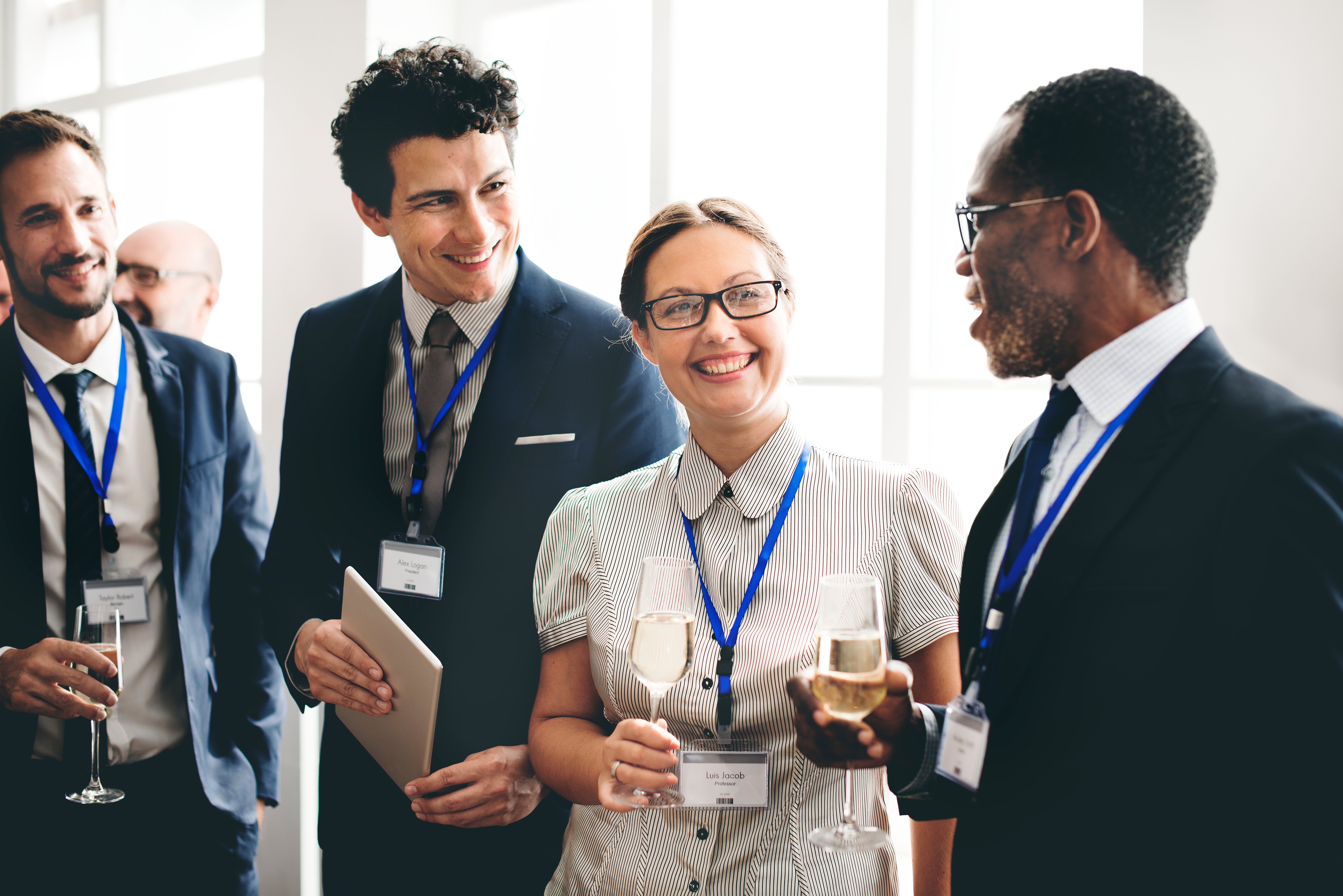A group of business people happily holding champagne glasses and exchanging pleasantries.