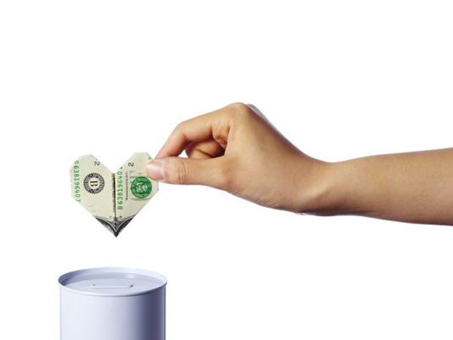 Donors Giving Less - Hand Putting Dollar in Can