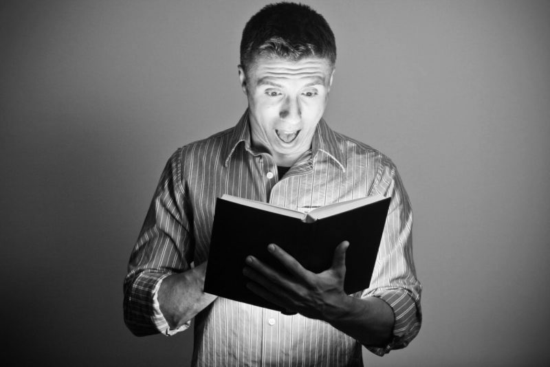 man reading a book with surprise