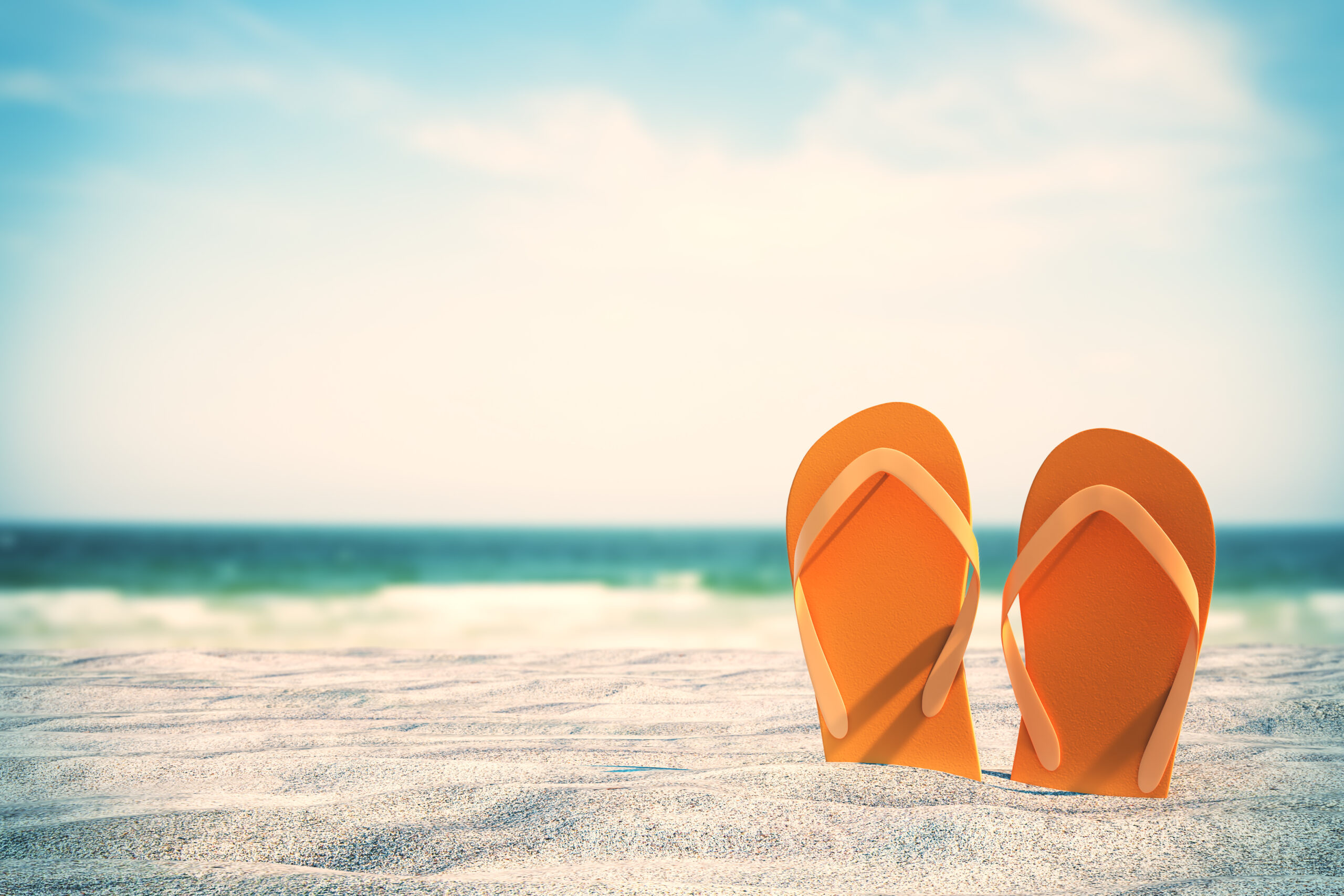 Orange flip flops sticking out of sand during beach vacation. [It's Time to Take a True Break]