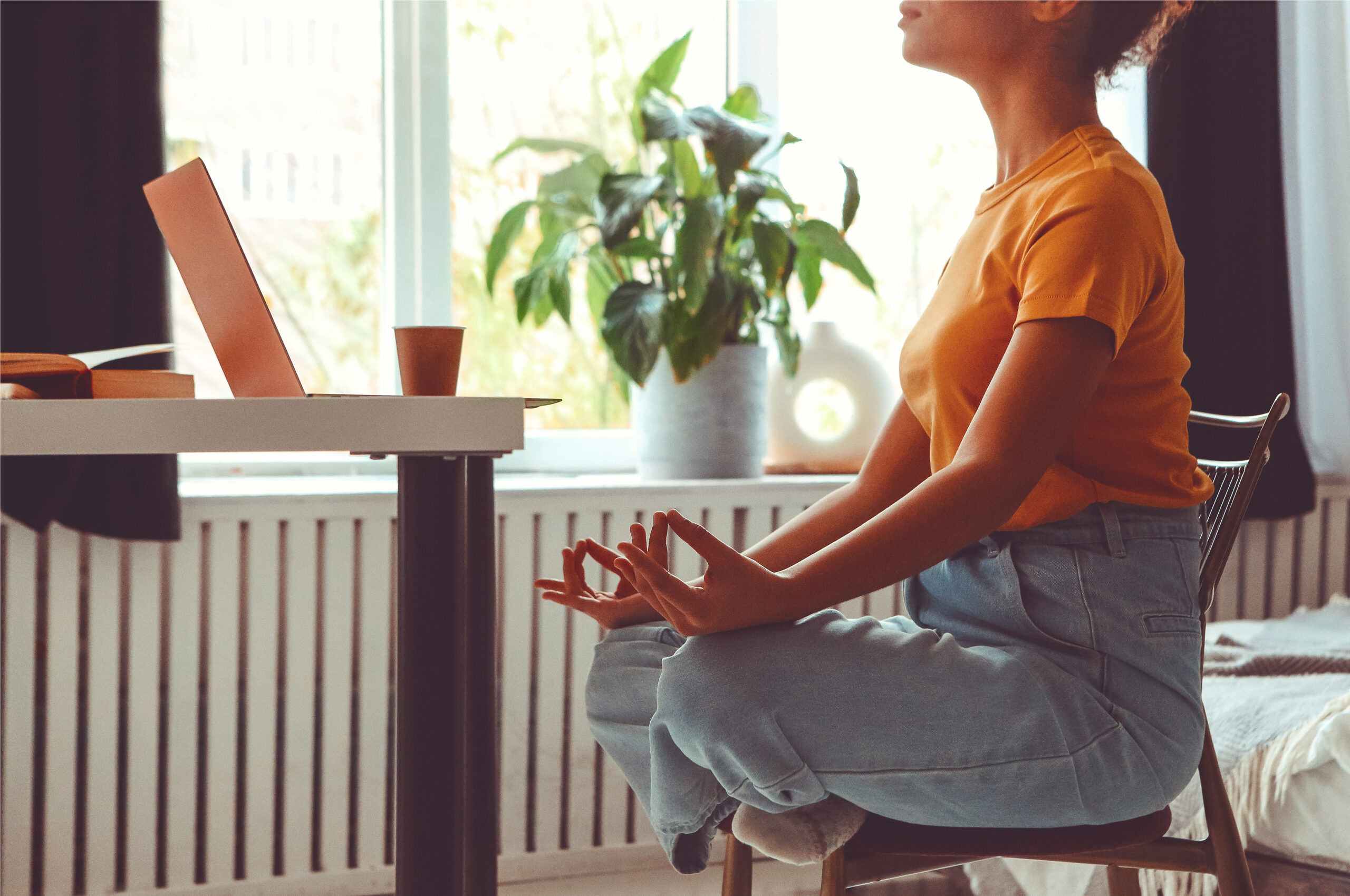Energy renewal: A woman meditating next to her laptop. [Stressed? Tired? Feeling Burnt Out? Here's How to Renew Your Energy]