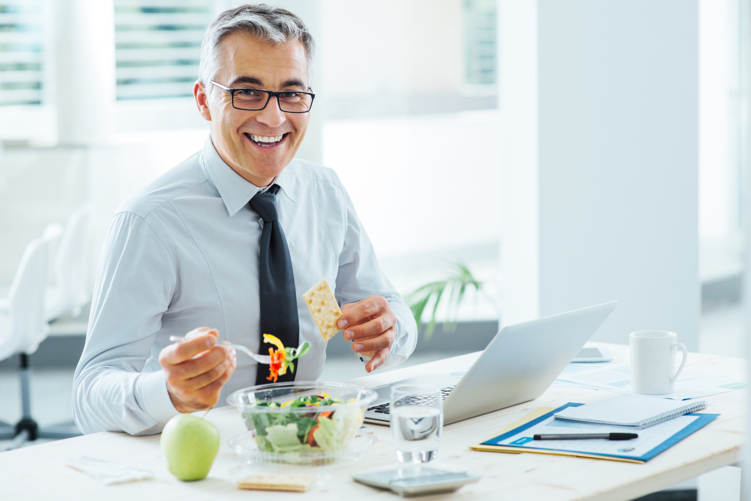Businessman eats lunch at desk. [Great MGOs Take Donors to a New Place, Not Out to Lunch]
