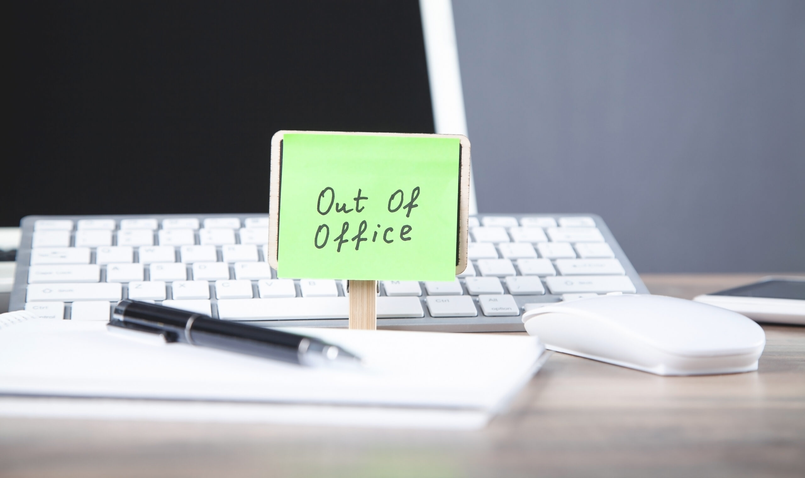 Out-of-office message on sticky note with computer [How to Write a Great Out-of-Office Message with Key Info for Your Donors]
