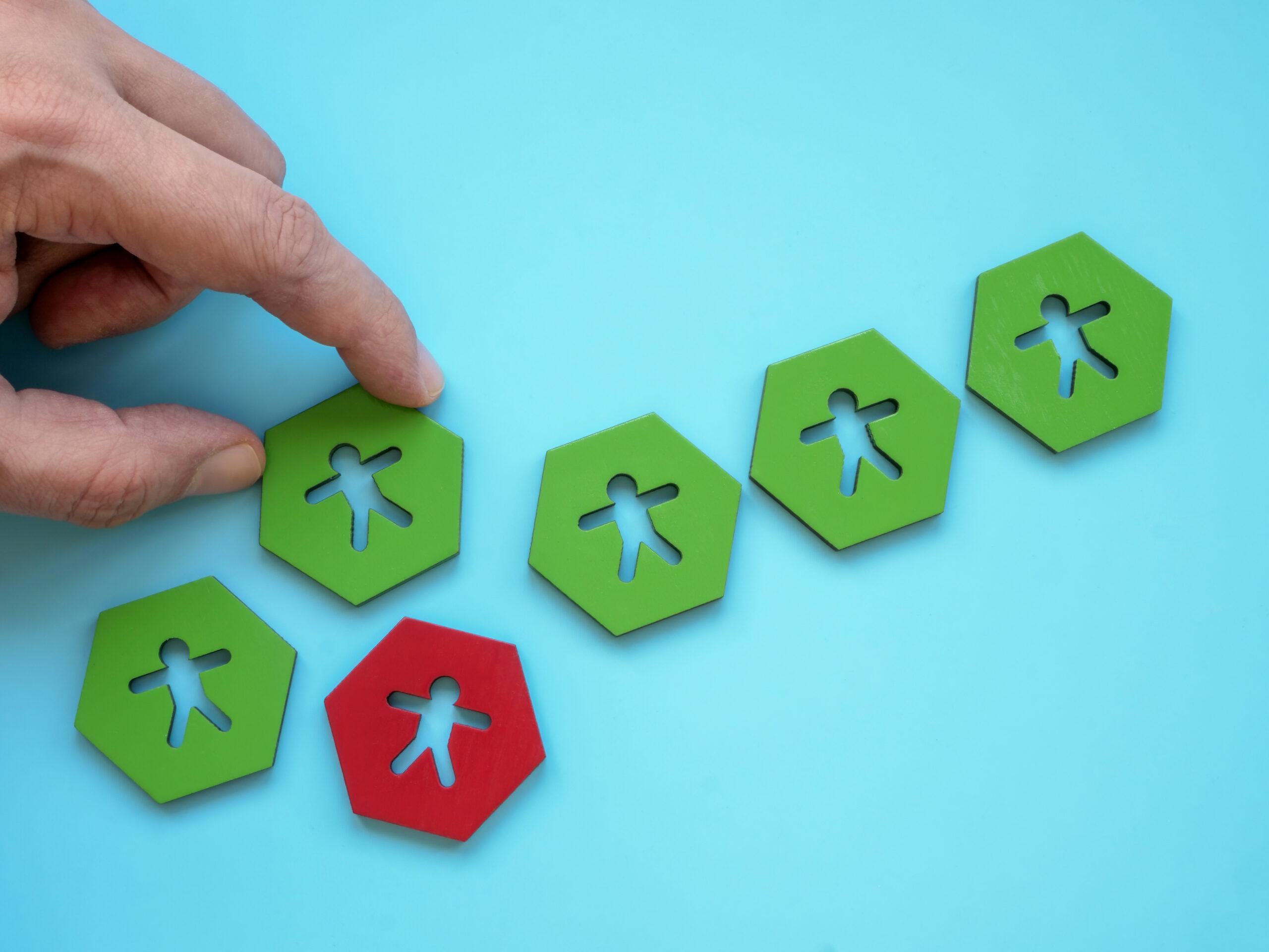 Image of hand choosing green token, representing the right person, in place of red. [Three Steps to Make Sure You Stop Hiring the Wrong Person]