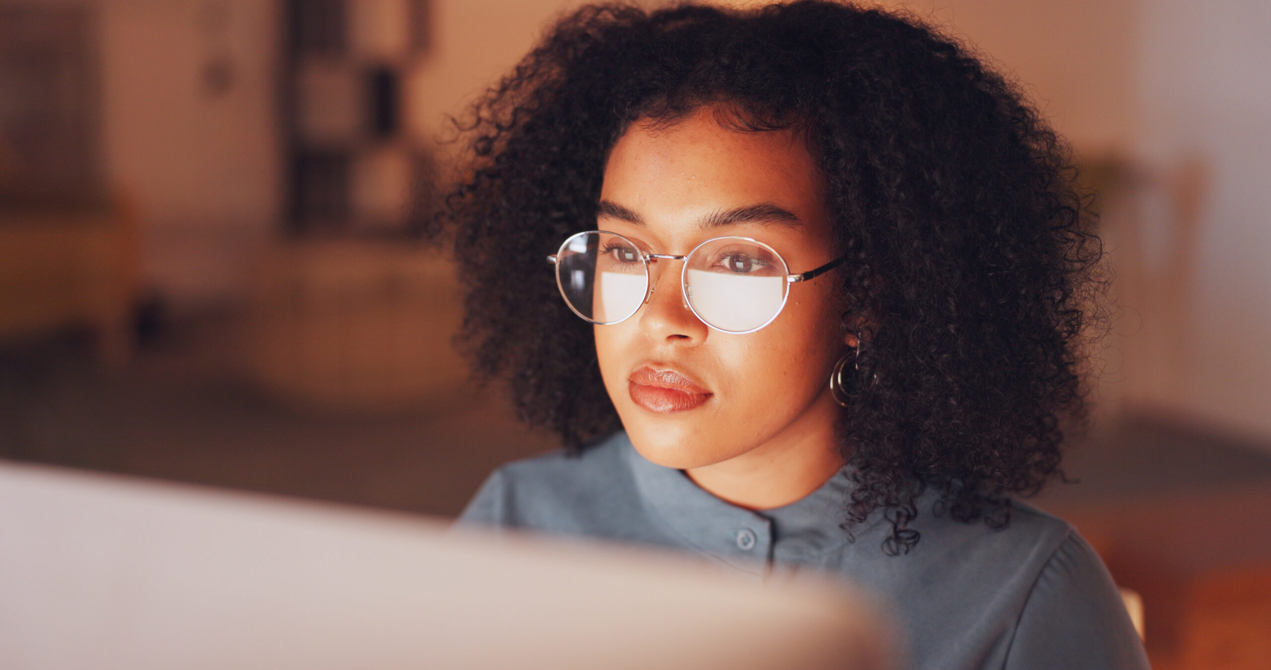 A woman looks at a laptop screen that's reflected in her glasses [For a Path to Sustainable Growth, Look Beyond Membership Programs]